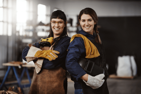 two women working as metal artwork artists smiling 